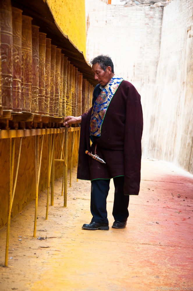 тибетец крутит молитвенные барабаны в монастыре Ронгву